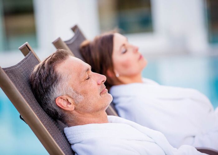 Paar beim relaxen im Liegestuhl am Pool